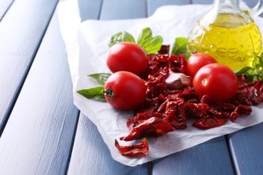 Güneş cam, cam şişe zeytinyağı, kurutulmuş domates, fesleğen yaprakları renk ahşap arka plan üzerinde