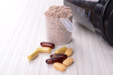 peynir altı suyu protein tozu kaşık vitaminler ve ahşap zemin üzerinde plastik shaker içinde