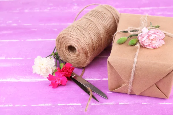 Schönes Geschenk mit Blumen und dekorativem Seil, auf altem Holzgrund — Stockfoto
