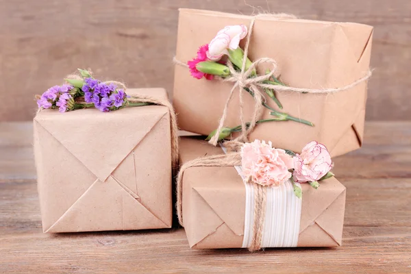 Prachtige geschenken met bloemen, op oude houten achtergrond — Stockfoto