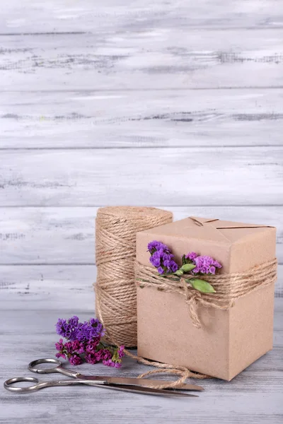 Beau cadeau avec des fleurs et une corde décorative, sur un vieux fond en bois — Photo