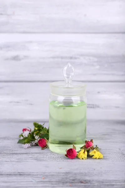 Essential oil with different medicine plants, on wooden background — Stock Photo, Image