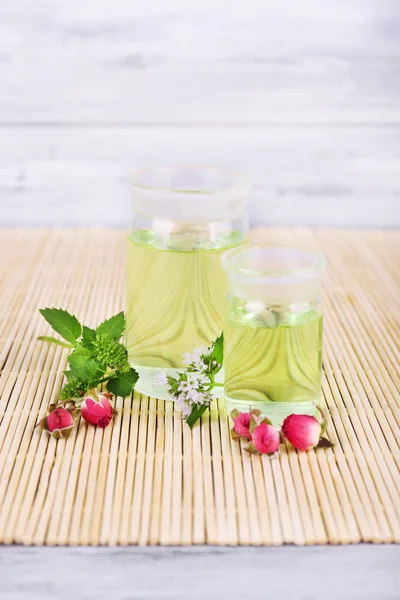 Essential oil with different medicine plants, on wooden background — Stock Photo, Image