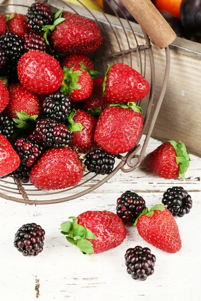Strawberries and blackberries in metal basket on table close up — Stock Photo, Image