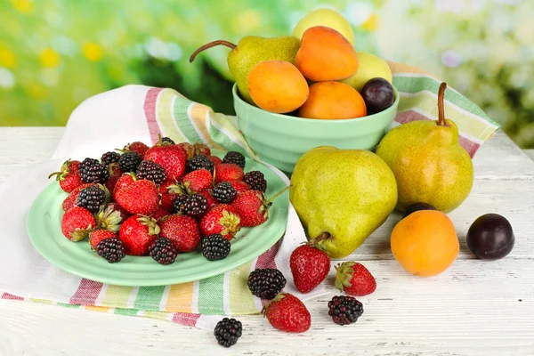 Frutas maduras y bayas sobre la mesa sobre fondo brillante — Foto de Stock