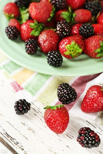 Fresas y moras en el plato en la mesa de cerca —  Fotos de Stock