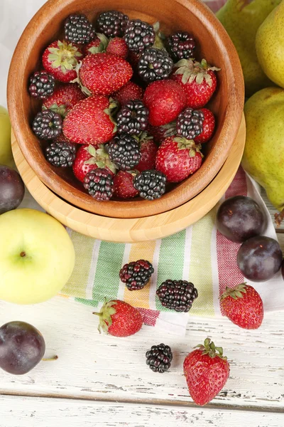 Las frutas maduras y las bayas en un tazón en la mesa de cerca —  Fotos de Stock