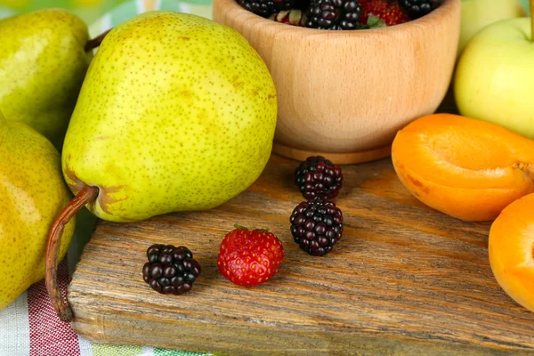 Buah matang dan buah beri dalam mangkuk di atas meja dekat — Stok Foto
