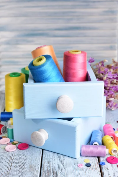 Accessori per cucire in scatole di legno sul tavolo su sfondo azzurro — Foto Stock