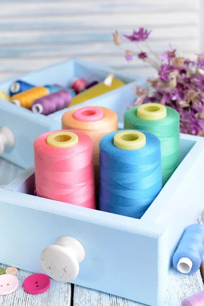 Naaien accessoires in houten kisten op tafel op lichte blauwe achtergrond — Stockfoto