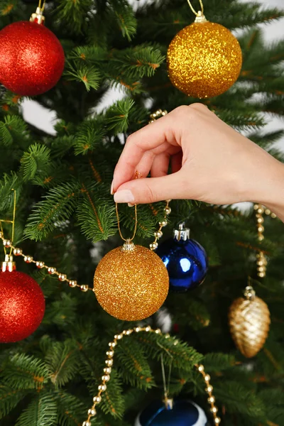 Bola de Natal na mão no fundo da árvore de Natal — Fotografia de Stock
