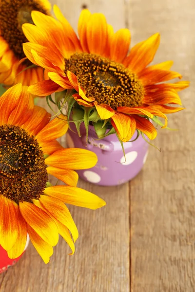 Beautiful sunflowers in cans on wooden background — Stock Photo, Image