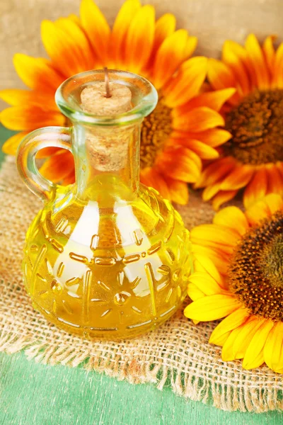 Sunflowers with oil on wooden background — Stock Photo, Image