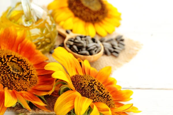 Sunflowers with oil and seeds on wooden background — Stock Photo, Image