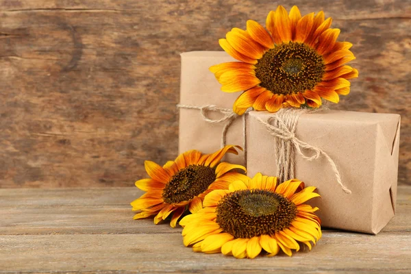 Sonnenblumen mit Geschenkschachteln auf Holzgrund — Stockfoto