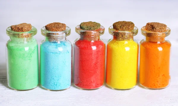 Botellas con coloridos pigmentos secos sobre fondo de madera — Foto de Stock