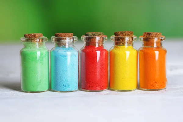 Botellas con coloridos pigmentos secos sobre fondo de madera — Foto de Stock