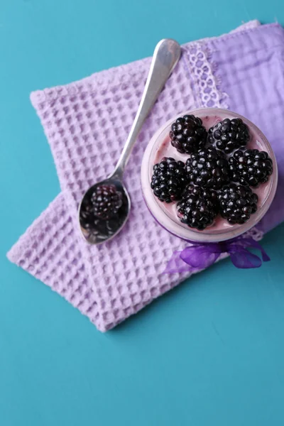 Colazione sana - yogurt con more e muesli servito in barattolo di vetro, su sfondo di legno a colori — Foto Stock