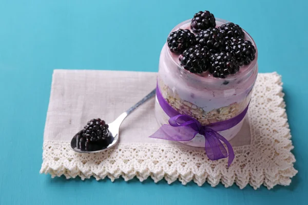 Healthy breakfast - yogurt with  blackberries and muesli served in glass jar, on color wooden background — Stock Photo, Image