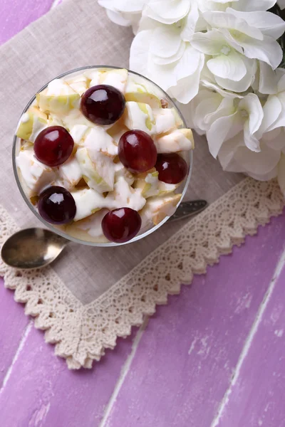 Desayuno saludable yogur con rodajas de uva fresca y manzana y muesli servido en un tazón de vidrio, sobre fondo de madera de color — Foto de Stock