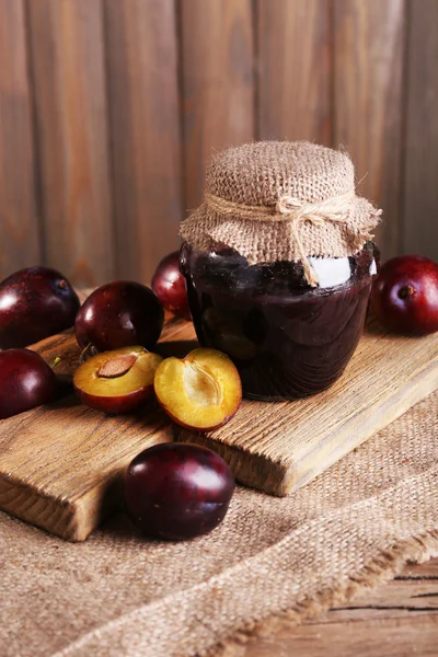 Confiture de prunes savoureuse en pot et prunes sur table en bois close-up — Photo