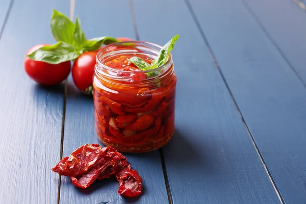 Tomates séchées au soleil dans un bocal en verre sur fond de bois couleur — Photo