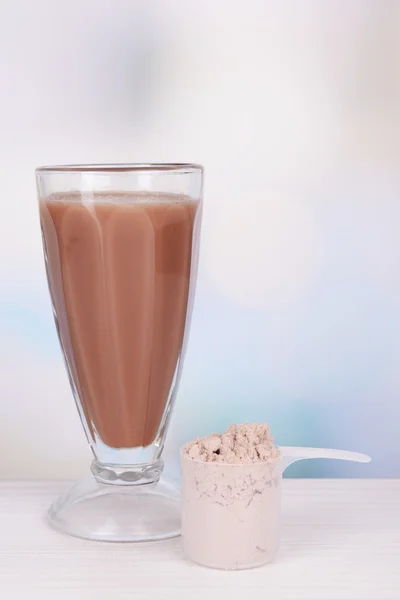 Polvo de proteína de suero y batido de proteína de chocolate en la mesa sobre fondo brillante — Foto de Stock