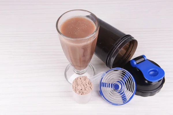 Proteína de suero en polvo con batido y agitador de plástico sobre fondo de madera —  Fotos de Stock