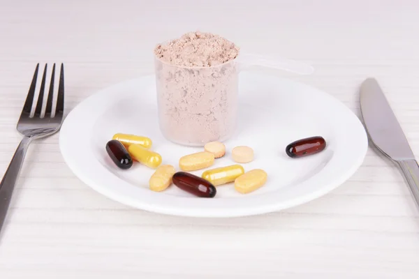 Vassleproteinpulver i scoop med vitaminer på plattan på trä bakgrund — Stockfoto