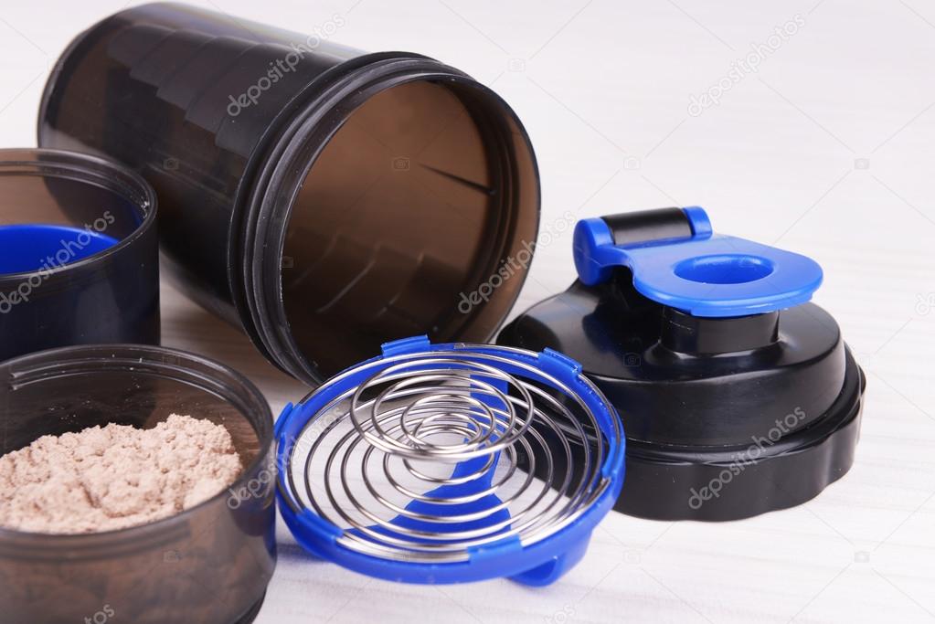 Whey protein powder and plastic shaker on wooden background