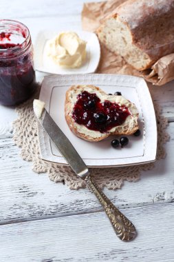 taze ekmek ile ev yapımı tereyağı ve blackcurrant jam hafif ahşap zemin üzerinde plaka üzerinde