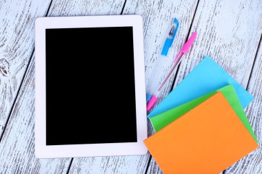 Tablet, not defteri ve kalemleri ahşap zemin üzerinde