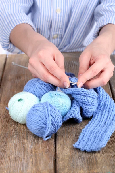 Hands knit scarf spokes on wooden table close-up — Stock Photo, Image