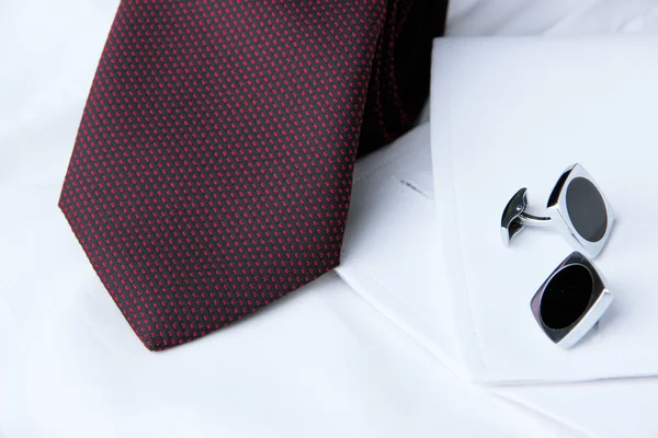 Un paio di gemelli su una manica della camicia bianca e una cravatta vicino ad essa — Foto Stock