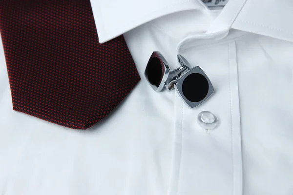 A pair of cuff links on a sleeve of the white shirt and a cravat near it — Stock Photo, Image