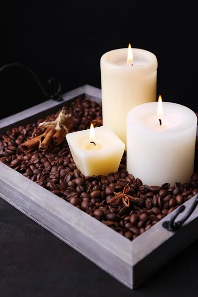 Candles on vintage tray with coffee grains and spices on wooden table, on dark background — Stock Photo, Image