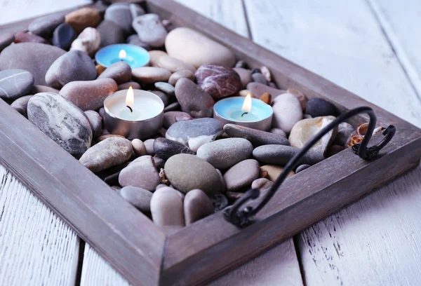 Kaarsen op vintage dienblad met zee kiezels, op houten achtergrond — Stockfoto