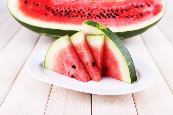 Slices of watermelon on plate on wooden background — Stock Photo, Image