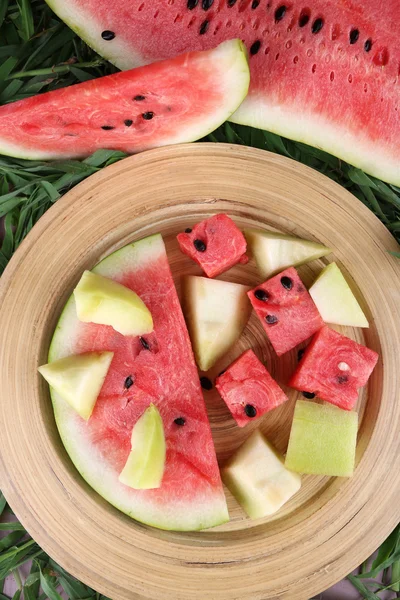 Water melon and melon on bamboo plate on grass background — Stock Photo, Image