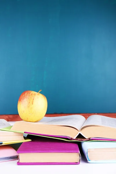 Schulbedarf auf Tisch auf Tafel-Hintergrund — Stockfoto