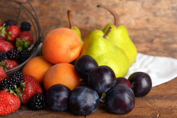 Frutas maduras y bayas en bandeja sobre fondo de madera — Foto de Stock