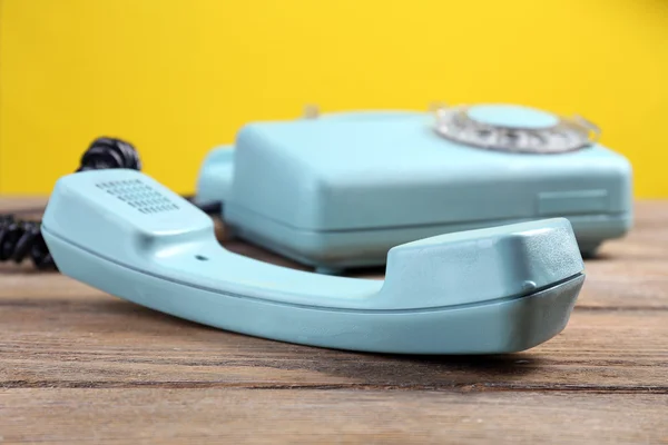 Retro turquoise telephone on wooden table, on color background — Stock Photo, Image