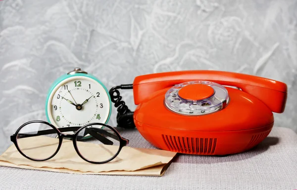 Teléfono retro, reloj y vasos en la mesa en la habitación —  Fotos de Stock