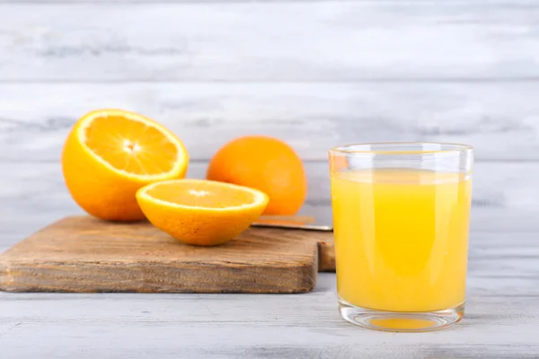 Glass of juice with fresh orange on grey wooden table — Stock Photo, Image