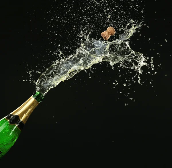 Bottle of champagne with splashes on black background Stock Picture