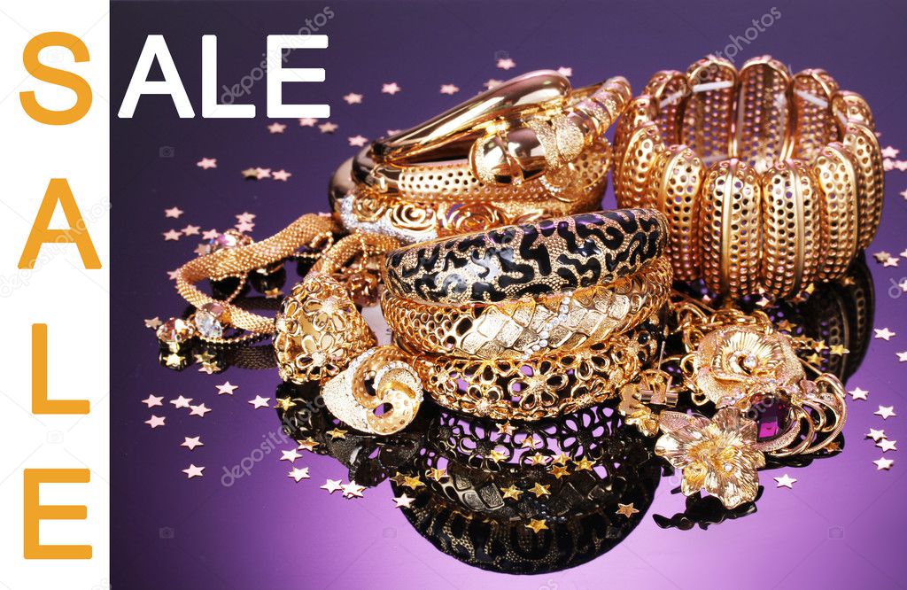 Concept of discount. Beautiful golden jewelry on purple background