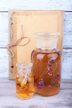 şişe bitki tentür, kitap ve ahşap zemin üzerinde kurutulmuş gül 