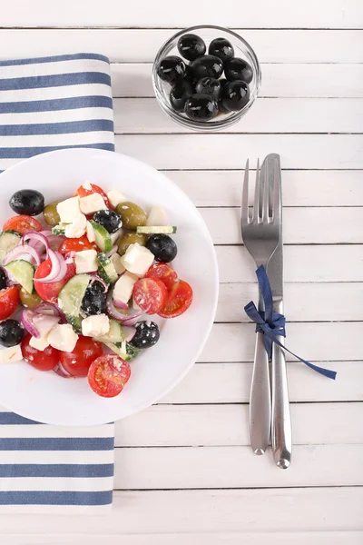 Greek salad served in plate on napkin on wooden background — Stock Photo, Image