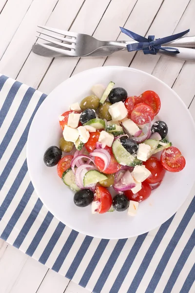 Kreikan salaatti tarjoillaan lautasella lautasliina puinen tausta — kuvapankkivalokuva