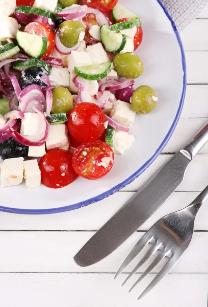 Griechischer Salat, serviert im Teller auf Holzboden — Stockfoto